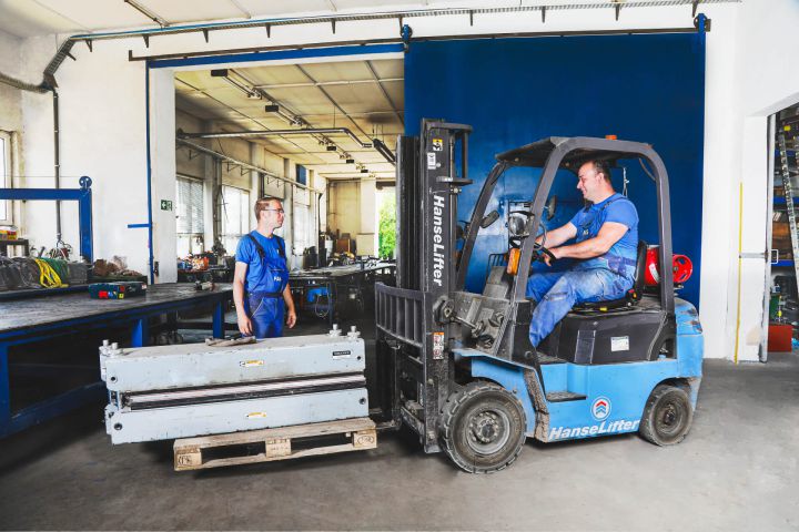 FAS-Mitarbeiter arbeiten mit Gabelstapler in der Werkstatthalle